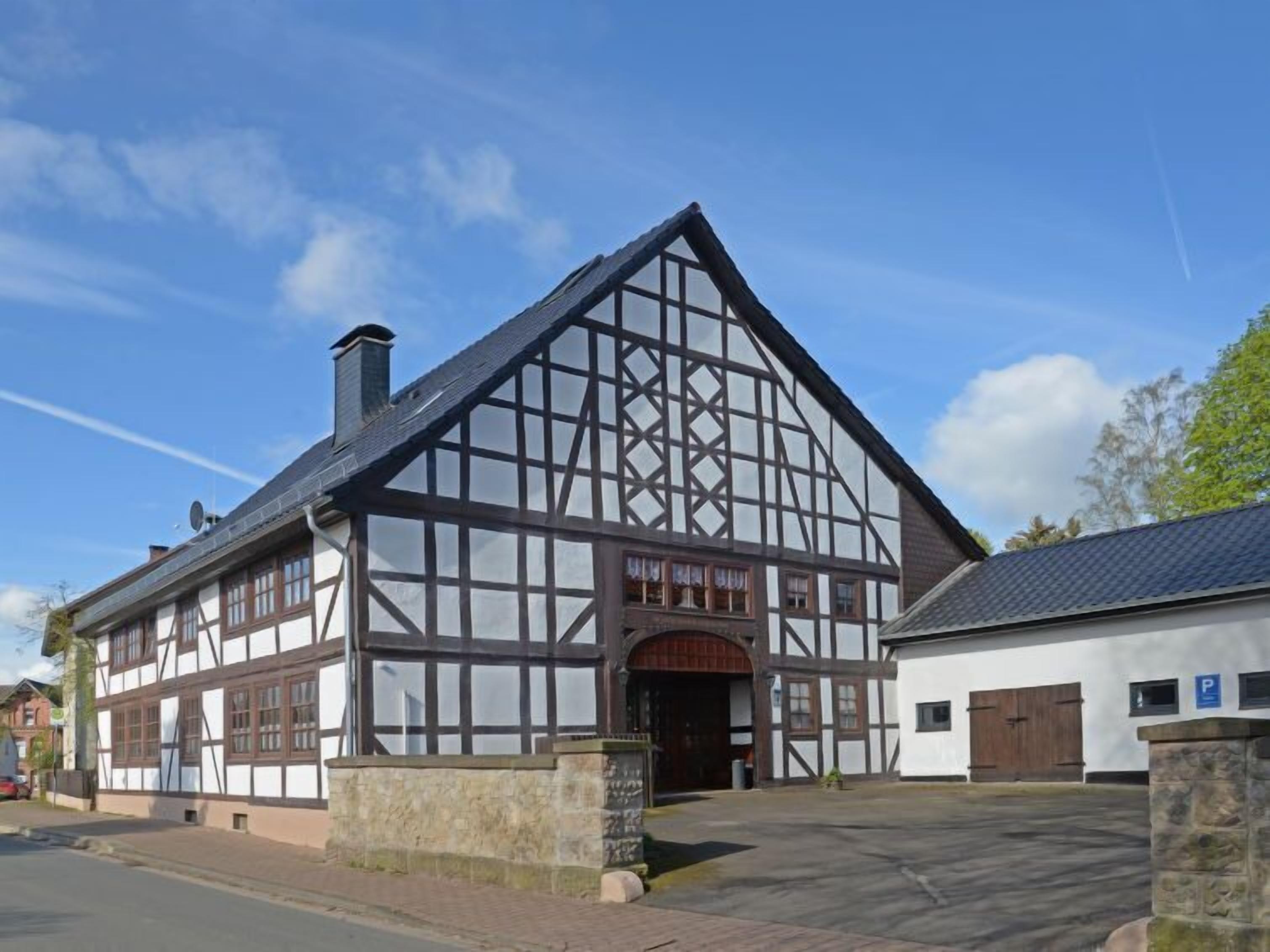 Un bâtiment traditionnel à colombages, doté d’une grande entrée et d’un mur de pierre à l’avant.