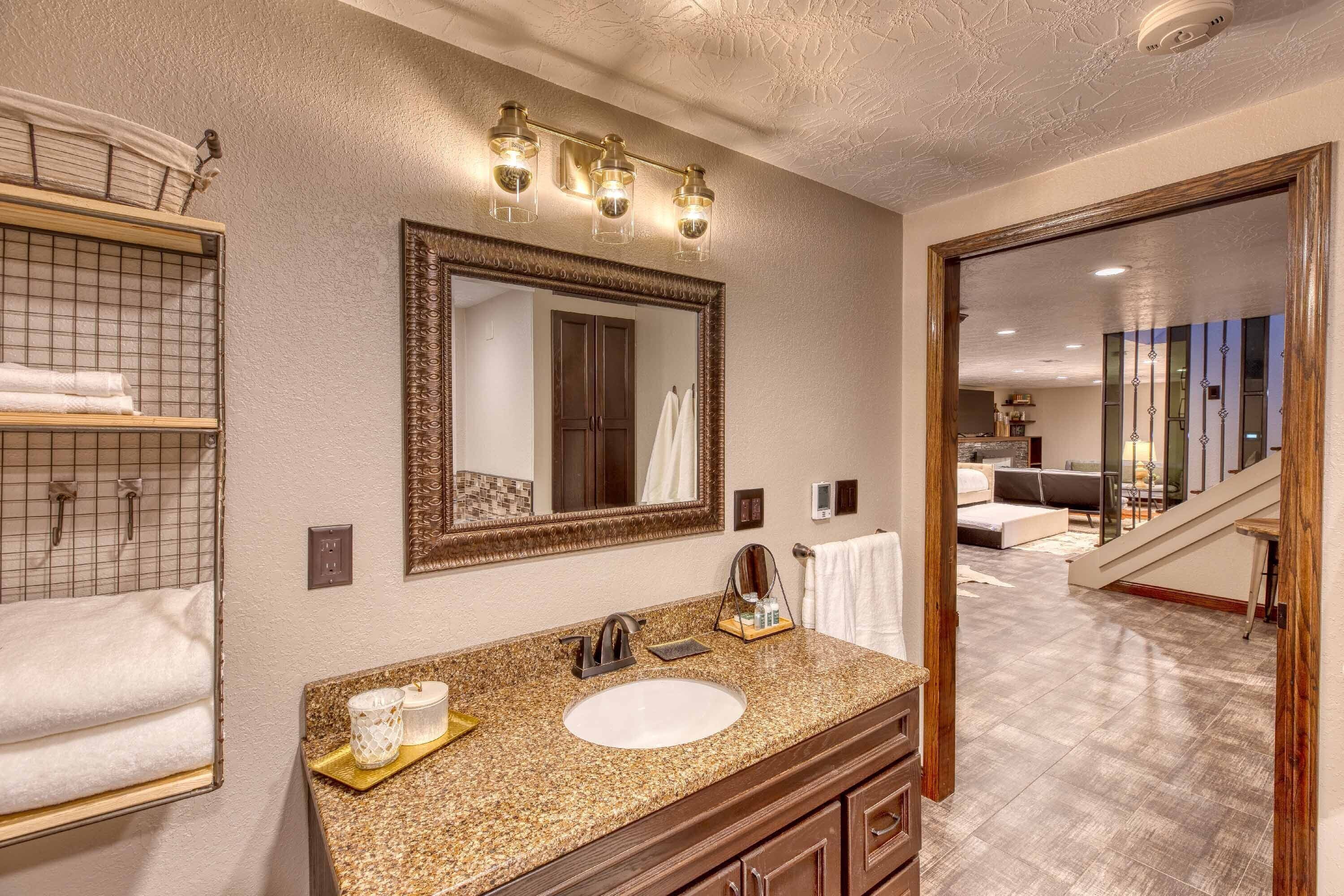 Une salle de bain avec un grand miroir, un lavabo et un porte-serviettes.