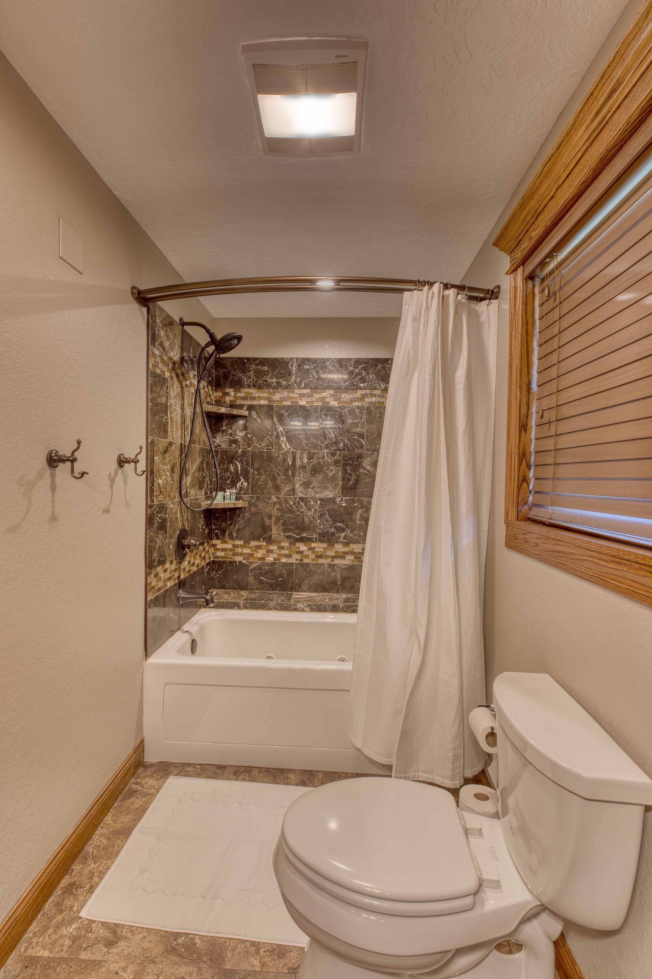 A bathroom with a bathtub, toilet, and shower curtain.