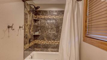 A bathroom with a bathtub, toilet, and shower curtain.