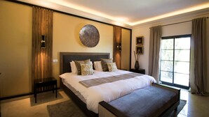 A modern bedroom with a large bed, bedside tables, a round wall decoration, and a large window with curtains. - Villa Emerald - tasteful and well presented villa (Almancil)