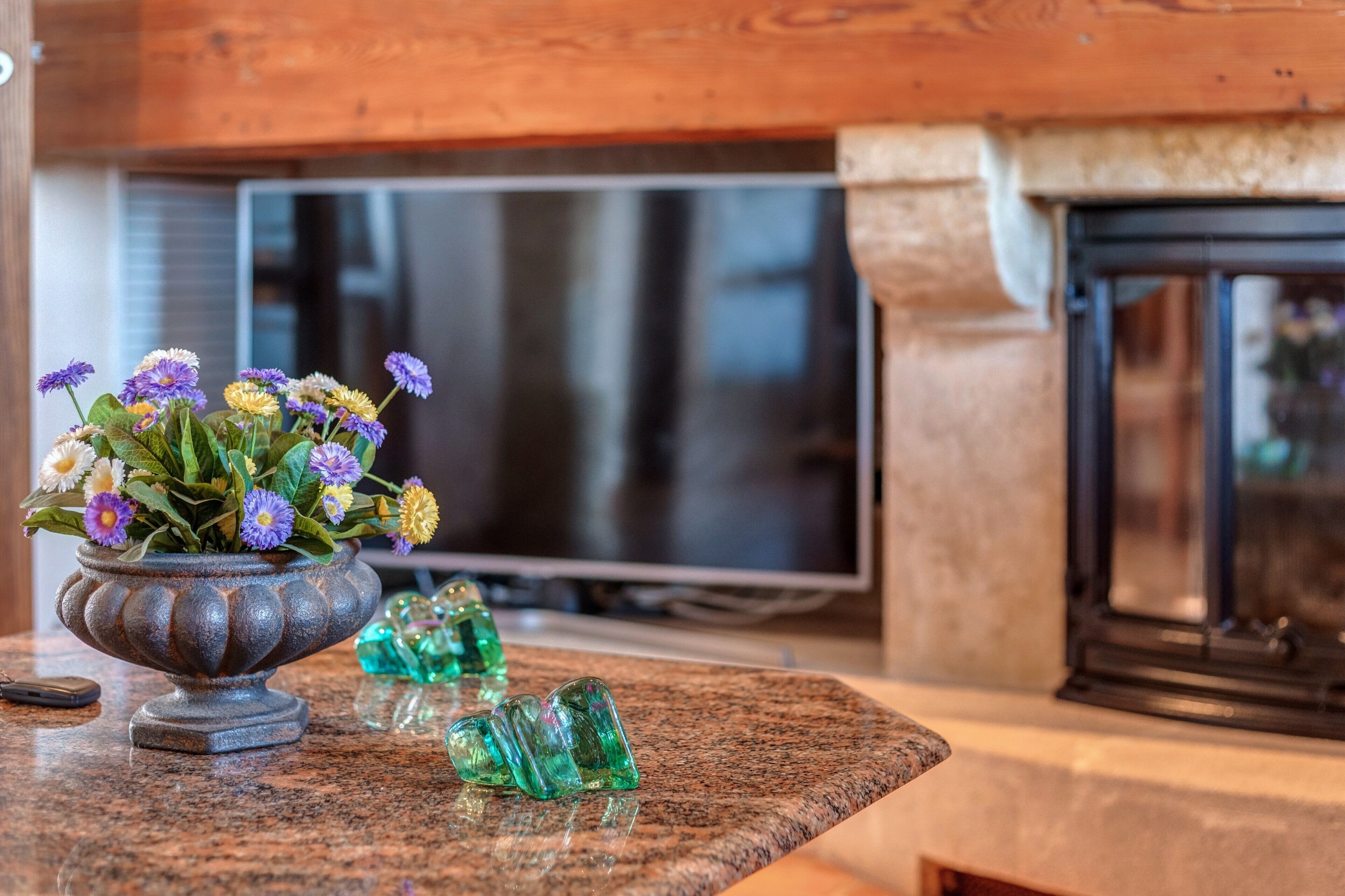 Ett kök med en bänkskiva i granit, en dekorativ skål med blommor och en tv-apparat i bakgrunden.
