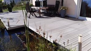 A deck with outdoor furniture, a potted plant, and a water feature.