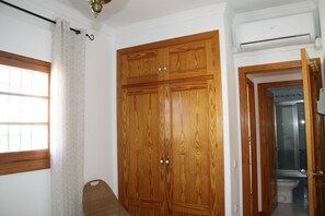 A room with a wooden wardrobe, a window with a curtain, and an air conditioning unit. - Lovely apartment for 4 guests with A/C, WIFI, TV and terrace (Chipiona)