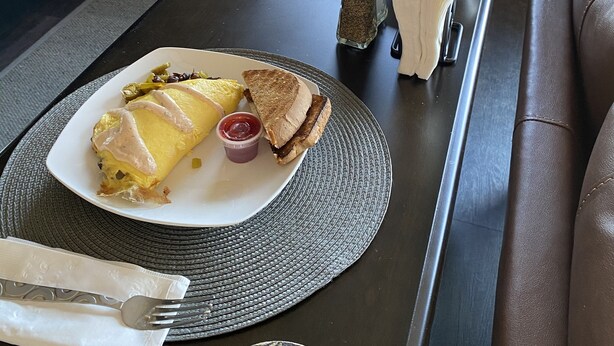 Ein Essbereich mit einem Tisch, der für das Frühstück gedeckt ist, darunter ein Omelett, Toast und eine Tasse Kaffee.