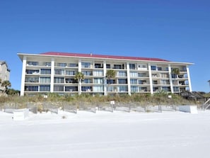Hotel de vários andares com telhado vermelho, situado perto de uma praia com areia.