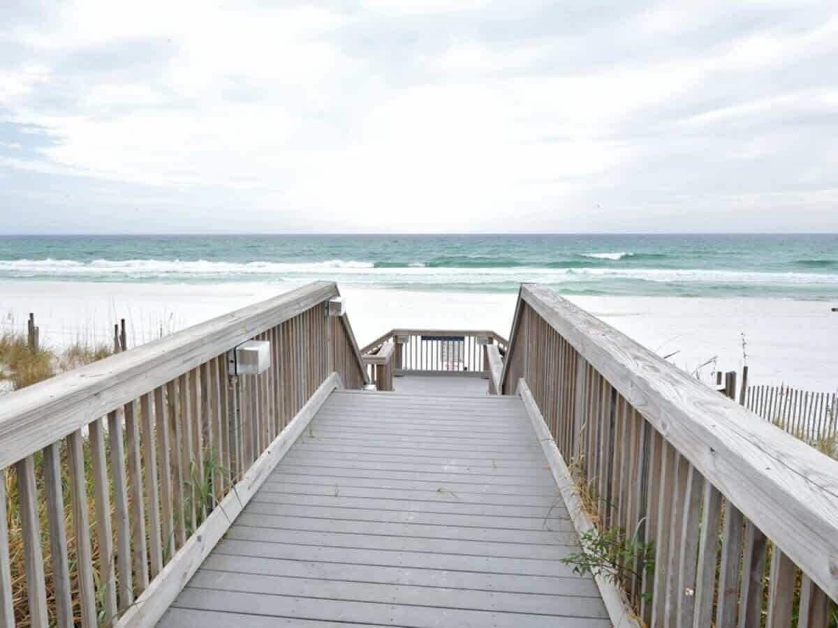 A wooden boardwalk leading to a beach with a view of the ocean.