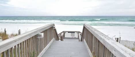 A wooden boardwalk leading to a beach with a view of the ocean.