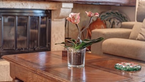 Una mesa de centro de madera con un florero de vidrio que contiene una planta y un posavasos decorativo.