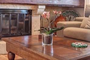 A wooden coffee table with a glass vase containing a plant and a decorative coaster.