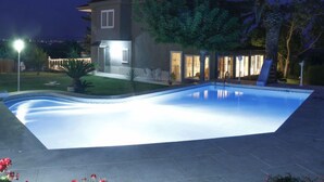 A swimming pool with a clear water surface, surrounded by a landscaped garden and a house with a visible patio area. - Ca Romeu by Interhome (Cambrils)