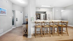 Une cuisine avec un plan de travail blanc, des chaises en bois et un réfrigérateur.