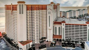 Un grand hôtel à plusieurs étages, doté d’un parking et offrant une vue sur l’océan.