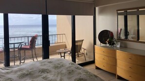 Un dormitorio con cama, cómoda, espejo y balcón con silla y mesa.