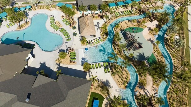 Luchtbeeld van een resort met meerdere zwembaden, ligbedden en palmbomen.