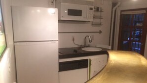 A compact kitchen with a refrigerator, microwave, sink, and a dishwasher. - DuPont - Scandinavian Café & Garden Apartment (Washington)