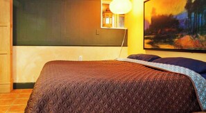 Relax in a warm and inviting space with a large bed, wall-mounted lamp, and decorative painting.