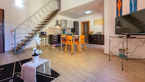 Un espacio habitable moderno con escalera, comedor, cocina y televisor de pantalla plana.