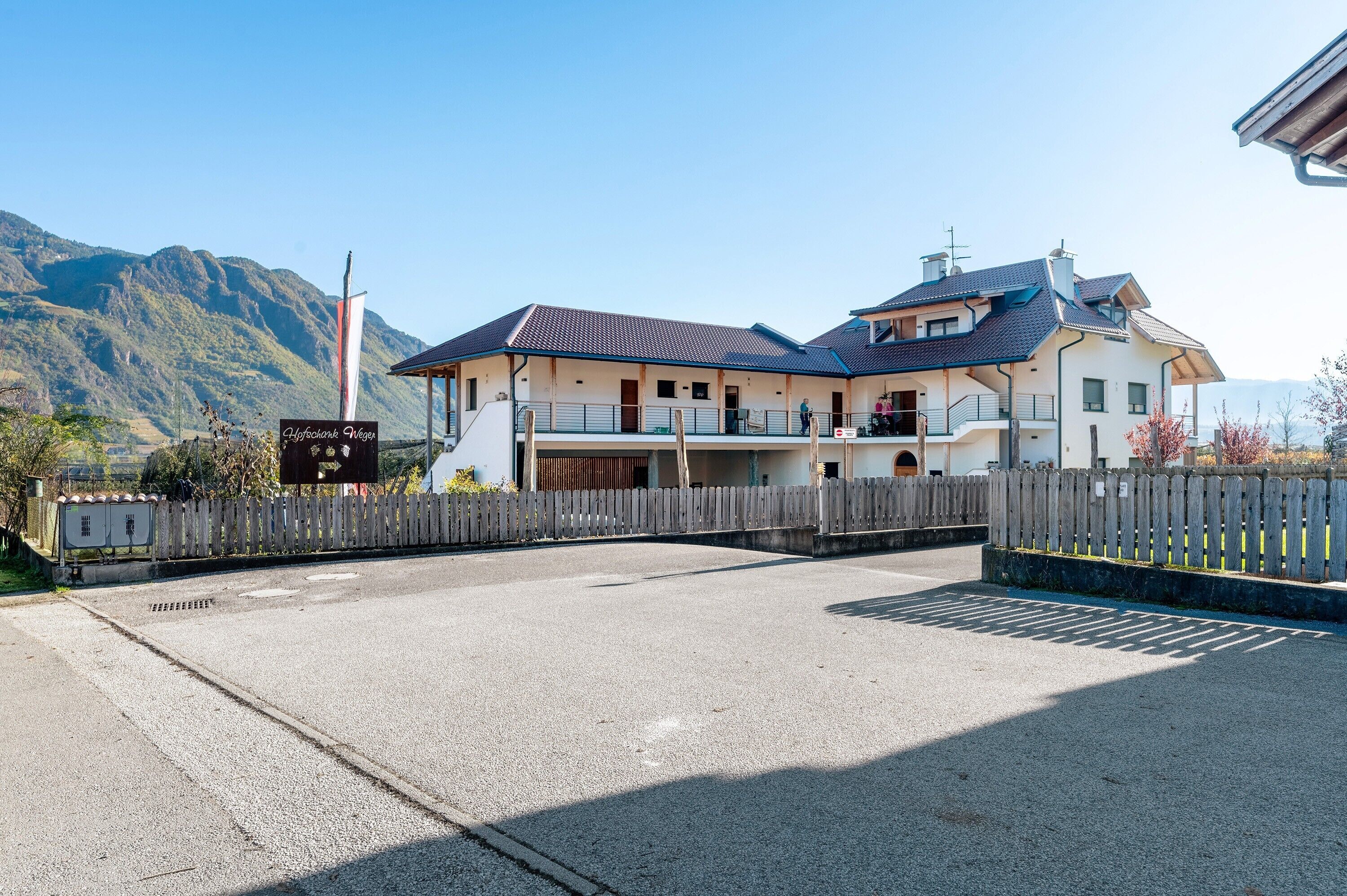 Ein Hotel mit großem Parkplatz, einem Schild mit der Aufschrift 'Hofbräuhaus' und einer Bergkulisse im Hintergrund.