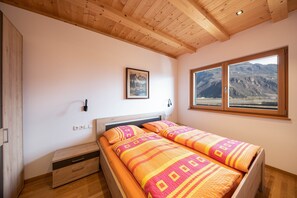 A bedroom with two beds, a wooden ceiling, a mountain view, and a framed picture on the wall. - Bright Apartment "1 Weger" with Panoramic Mountain View, Wi-Fi & Balcony (Andrian)