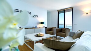Ein modernes Wohnzimmer mit einem weißen Sofa, einem Couchtisch und Meerblick durch große Fenster.