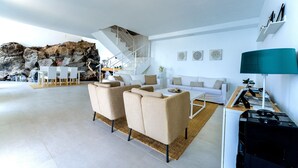 Ein modernes Wohnzimmer mit einer Sofagarnitur, einem Couchtisch, einer Lampe und einer Treppe, die auf einen Balkon führt.