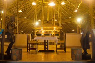 Un restaurante con un alto techo de madera, mesas dispuestas para comer y macetas de piedra.