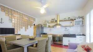 Una cucina compatta con zona pranzo, una ventola a soffitto e un televisore.