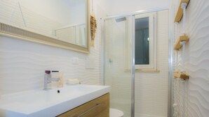 Un bagno con un mobile lavabo bianco, cabina doccia in vetro e parete strutturata.