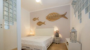 Una camera da letto con un letto, un comodino, una lampada a parete e un'opera d'arte decorativa a tema pesci.