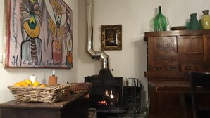 Ein Zimmer mit Kaminofen, einem Gemälde an der Wand und einer Holzkabine mit Schubladen.