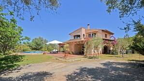 Una casa con piscina, mobiliario de exterior y jardín.
