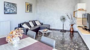 Un salon moderne avec un canapé, une table basse et un coin repas agrémenté d’un vase de fleurs.