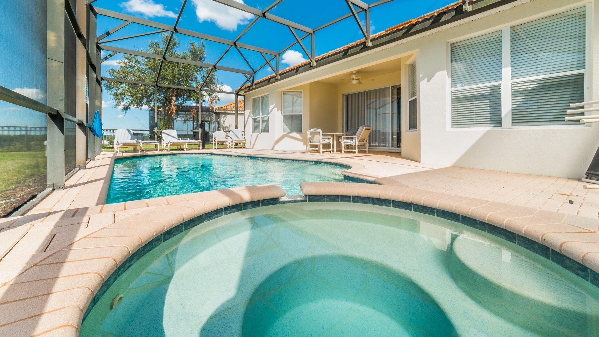 A swimming pool with a glass ceiling, surrounded by lounge chairs and a patio area.
