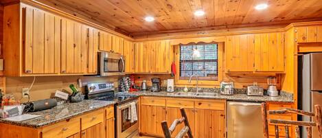 A kitchen with wooden cabinets, granite countertops, stainless steel appliances, and a dining area with a wooden table and chairs.