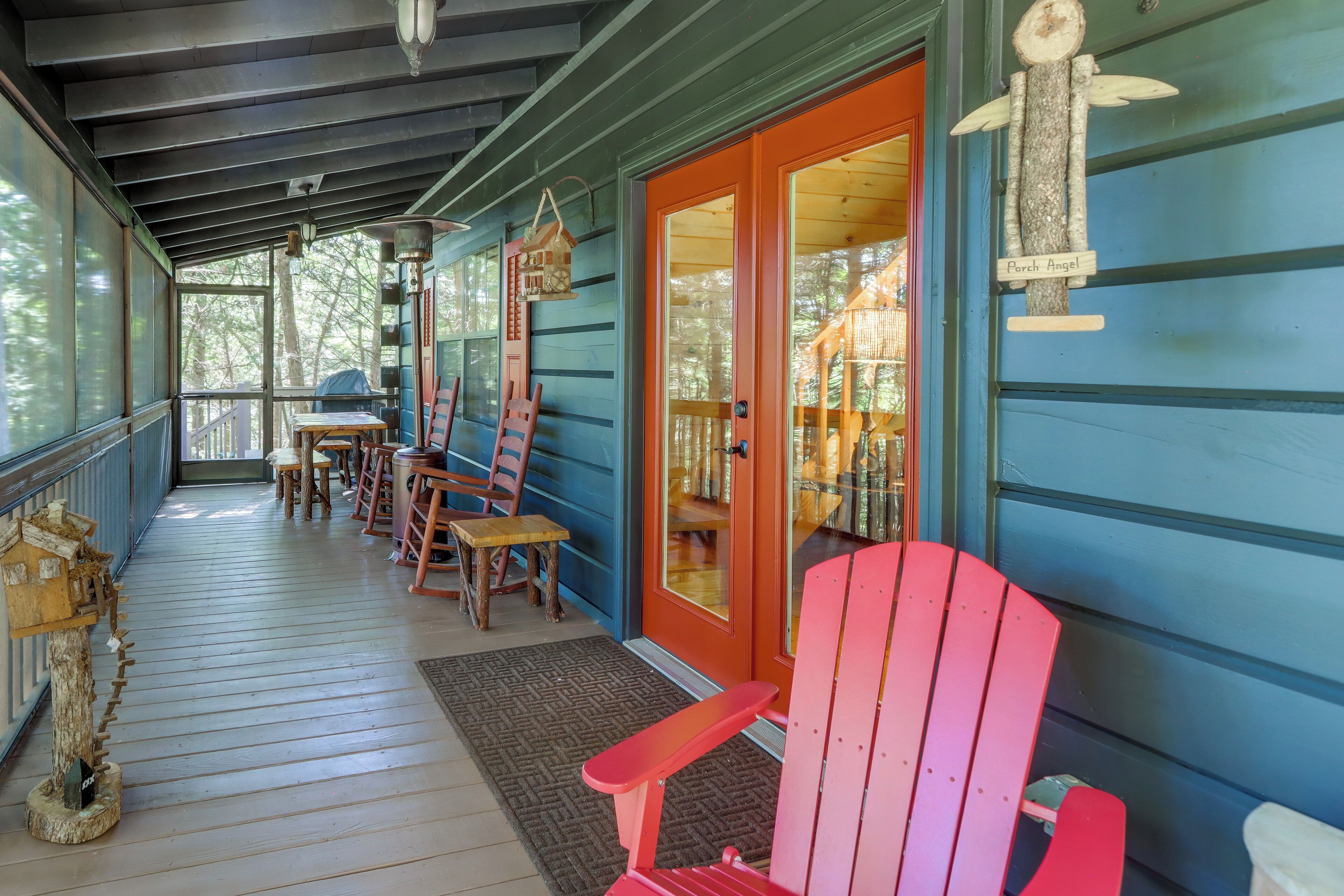 A covered porch with wooden chairs and tables, a wooden birdhouse, and a porch angel decoration.