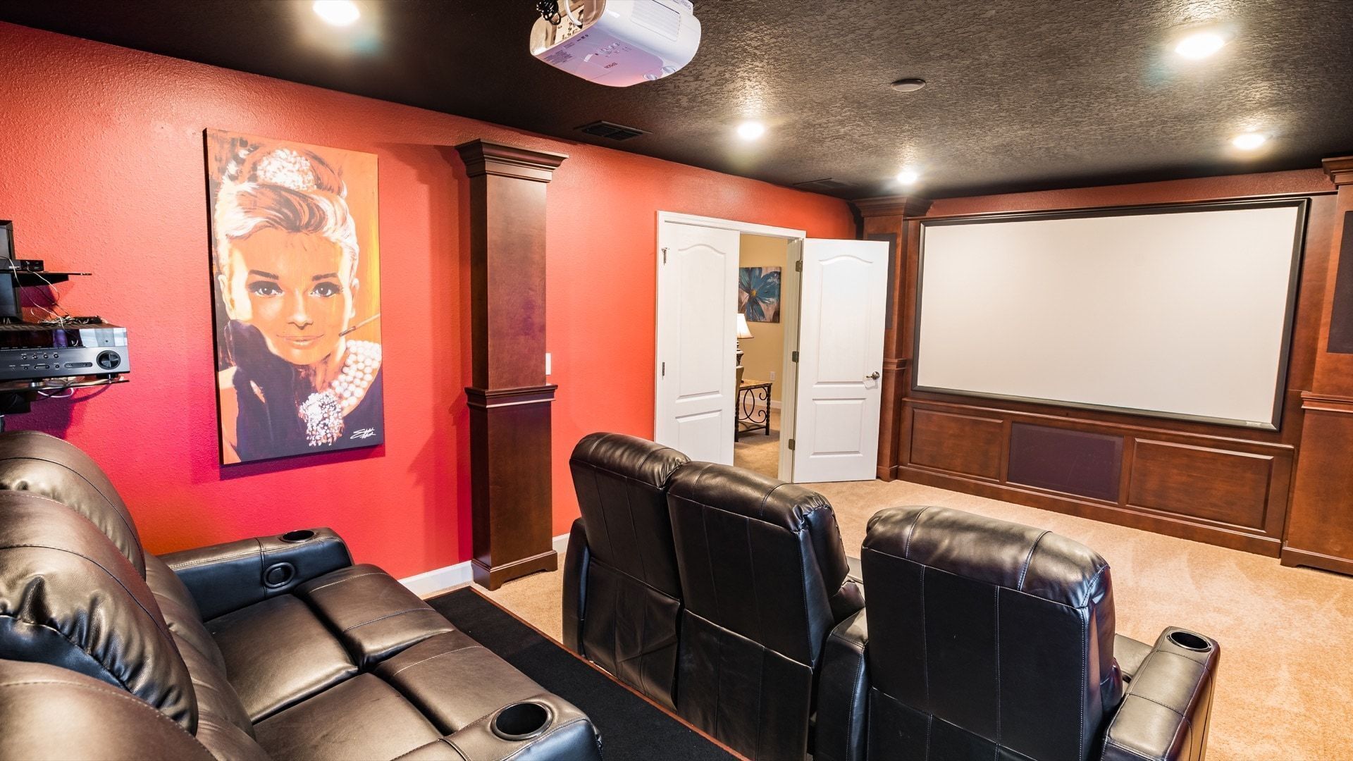 A home theater room with leather recliner seating, a large screen, and a projector.