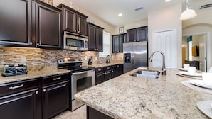 A modern kitchen with dark cabinetry, stainless steel appliances, granite countertops, and a built-in microwave. - New Listing! Paradise Palms Resort, 6mi to Disney & 14mi to Universal - GRH438930 (Kissimmee)