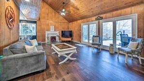 A spacious living room with a wooden ceiling, a fireplace, a television, and a large window. - Hot Tub: Secluded Hideaway on Sleepy Hollow Lake (Athens)
