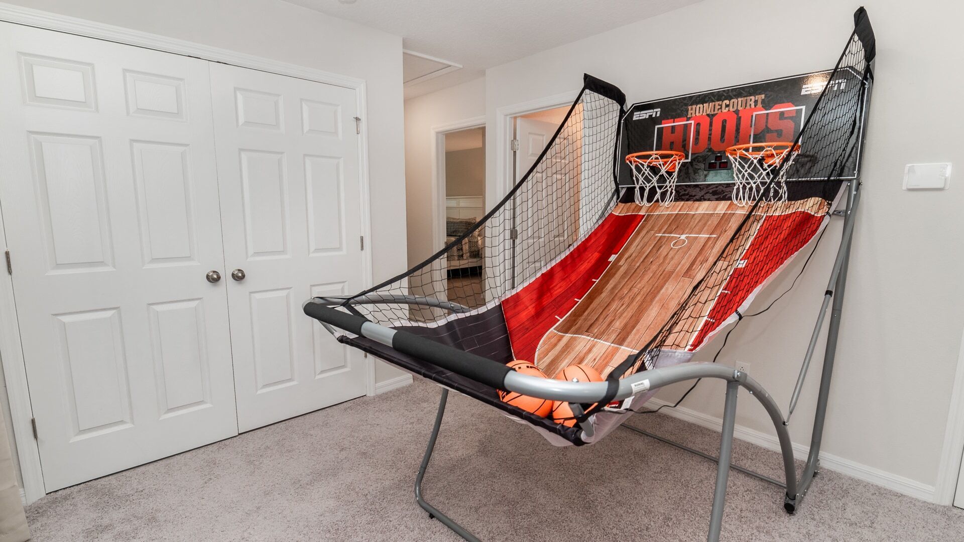 Ein Basketballplatz mit Rückwand und Korb in einer Halle mit weißen Türen.