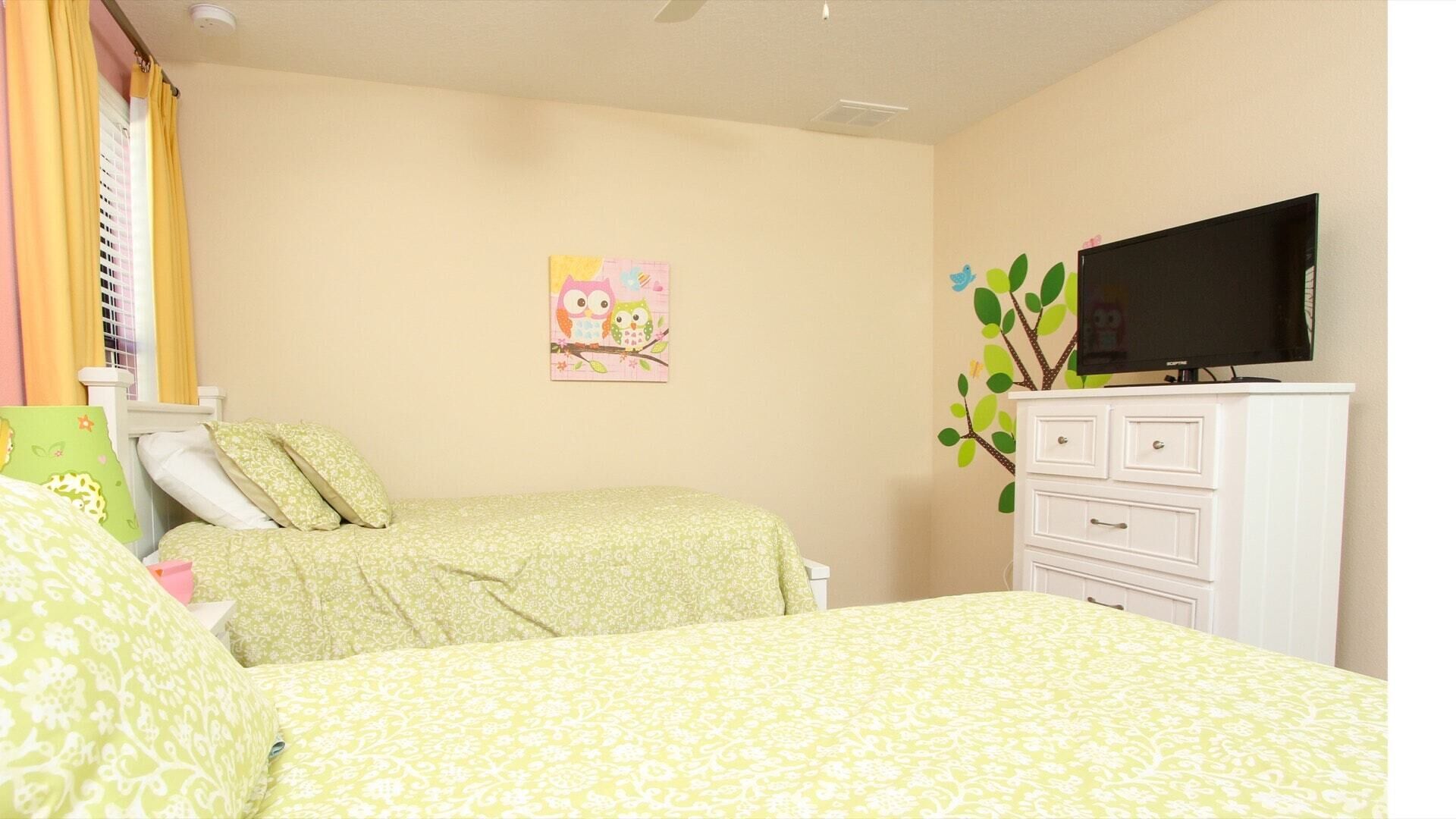 A bedroom with two beds, a dresser, a television, and a wall decoration.