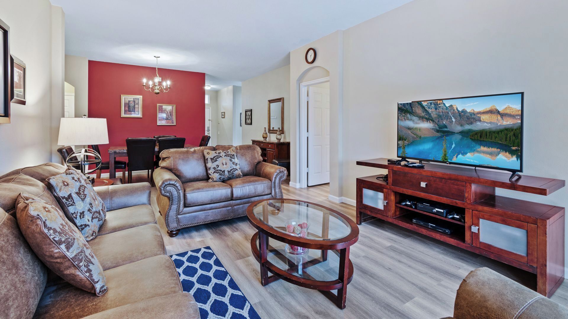 A living room with a leather sofa, a glass coffee table, and a wooden entertainment unit with a flat-screen TV.