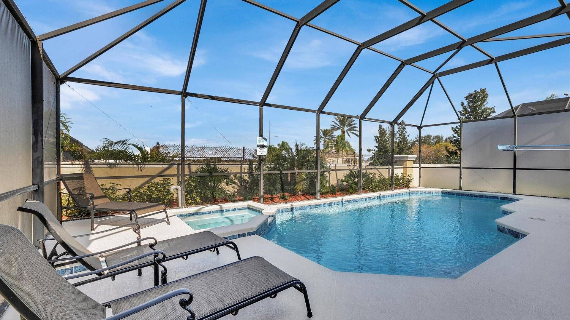 Une piscine extérieure couverte, dotée de chaises longues et offrant une vue sur les environs.