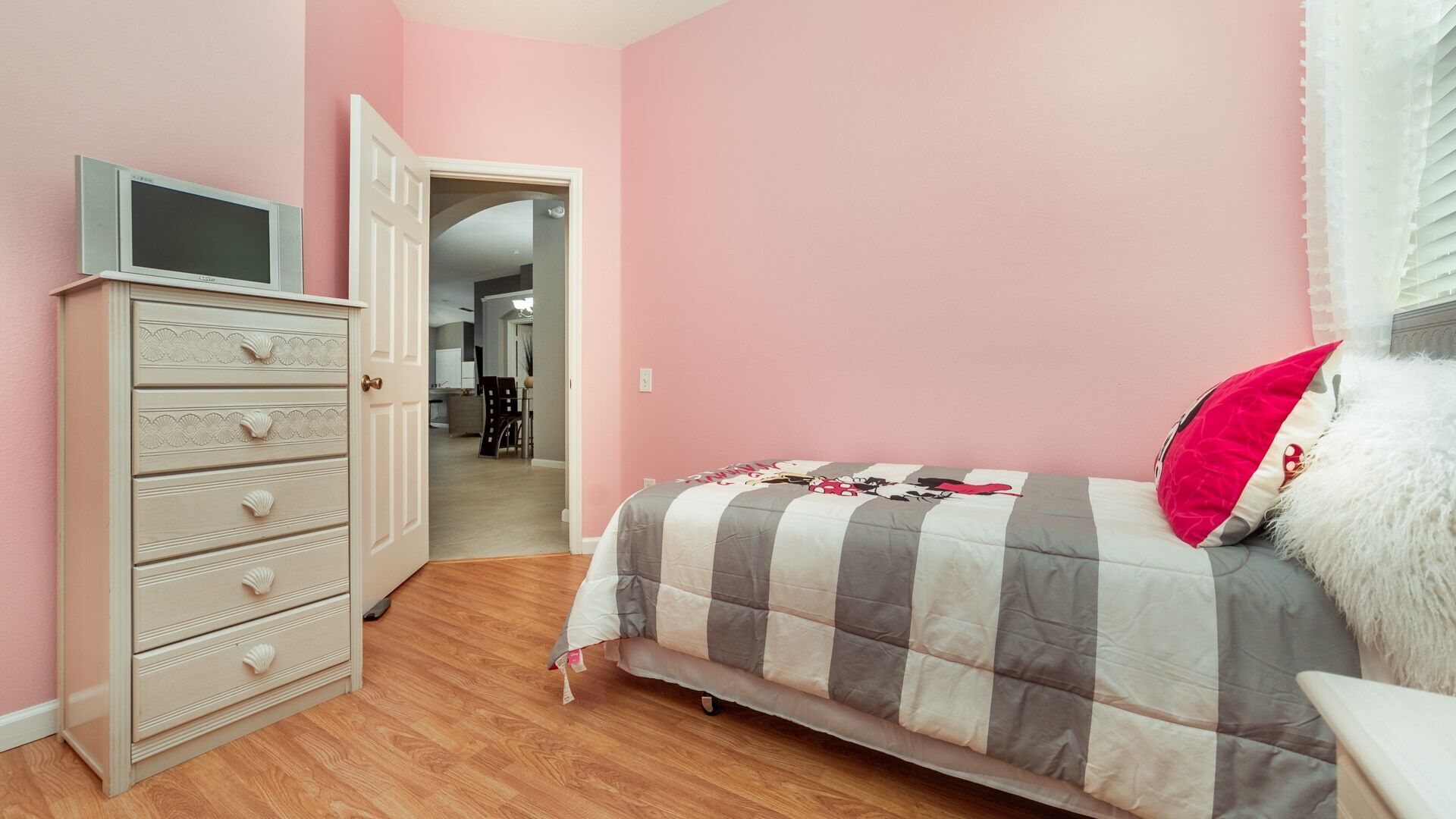 Un dormitorio con cama, cómoda y televisor.