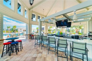 Enjoy refreshing drinks and entertainment by the pool in this outdoor bar area with comfortable seating and a large screen TV.