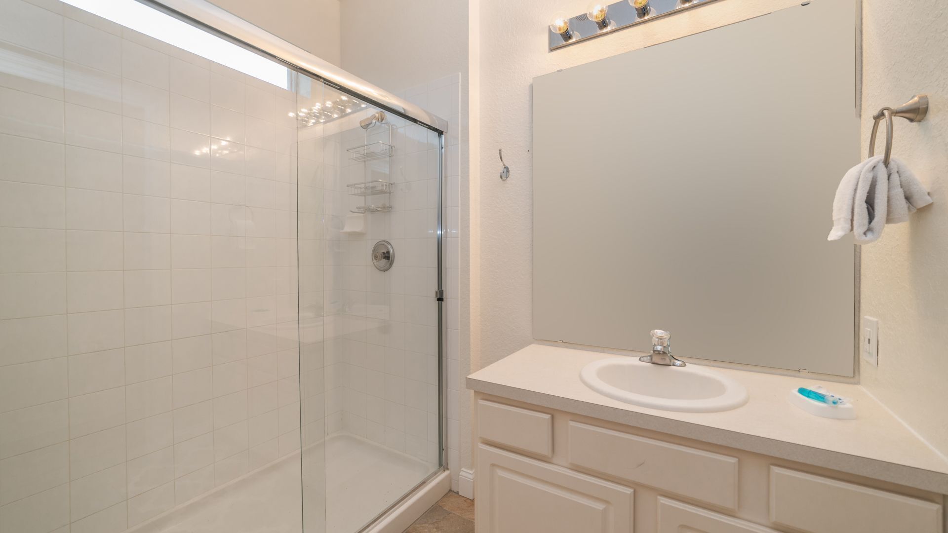 A modern bathroom with a glass shower enclosure, a white sink, and a large mirror.
