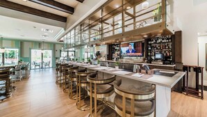 A modern bar area with a long counter, multiple stools, and a television screen. - New Listing! Solara Resort, 8mi to Disney & 15mi to Universal - GRH438809 (Kissimmee)