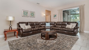 A living room with a brown leather sectional sofa, a wooden coffee table, a rug, and framed artwork on the walls.