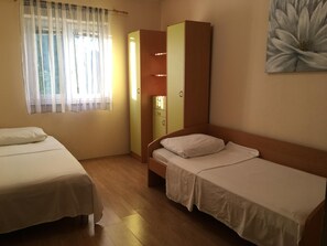 Una habitación con dos camas individuales, un armario y un cuadro en la pared.