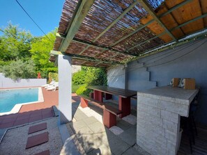 Un espacio exterior cubierto con piscina, mobiliario y una estación de barbacoa.